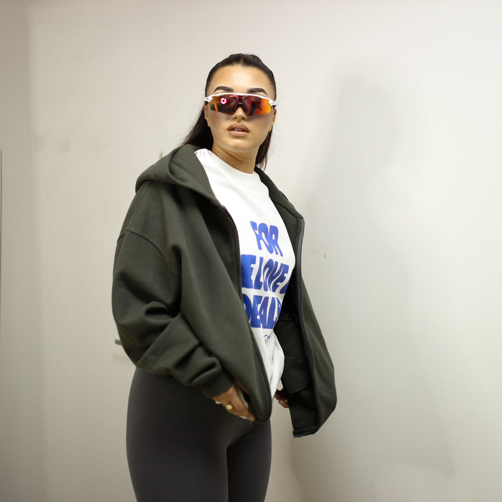 Ashe Zip-Up Hoodie in dark green worn by a model indoors.