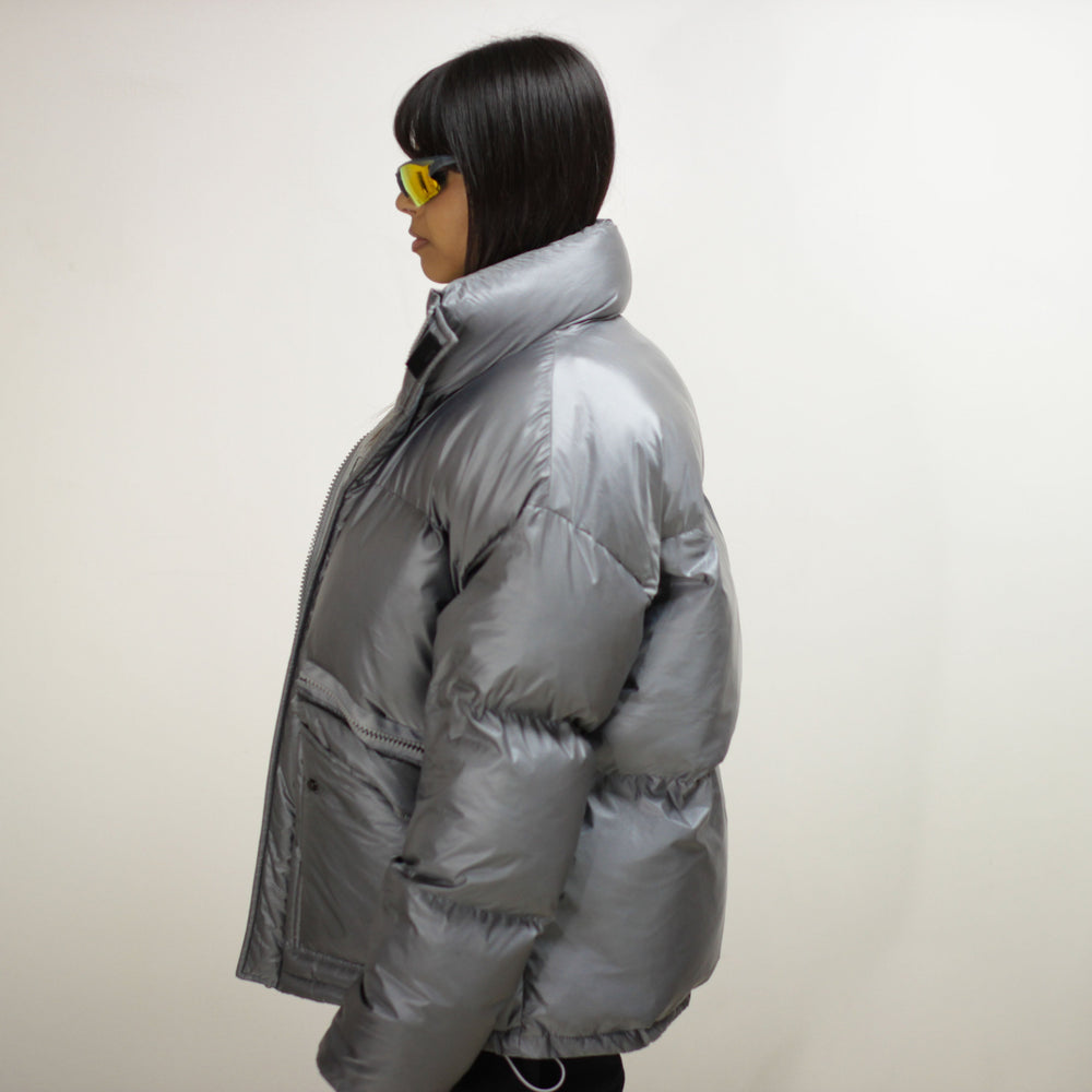 Side view of a silver padded round jacket on a model.