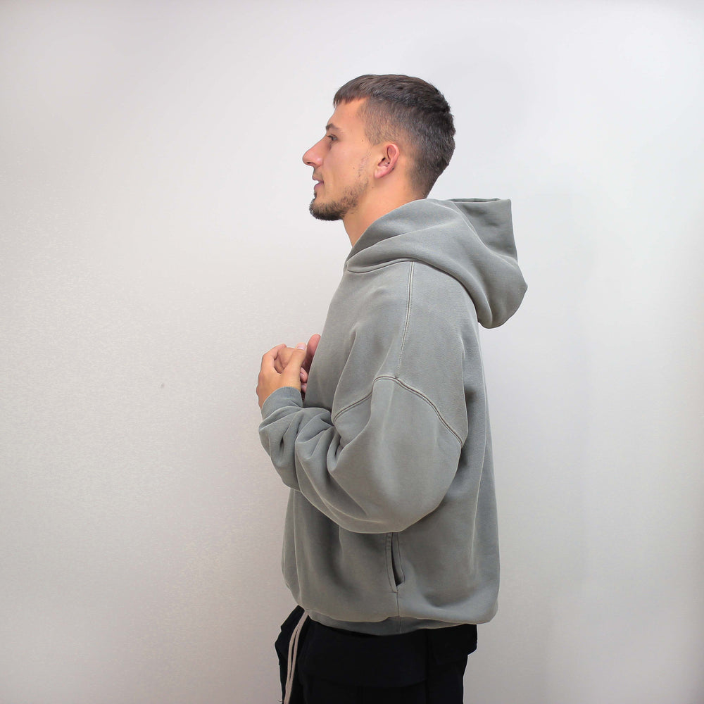 Gray round hoodie worn by a person, side view.
