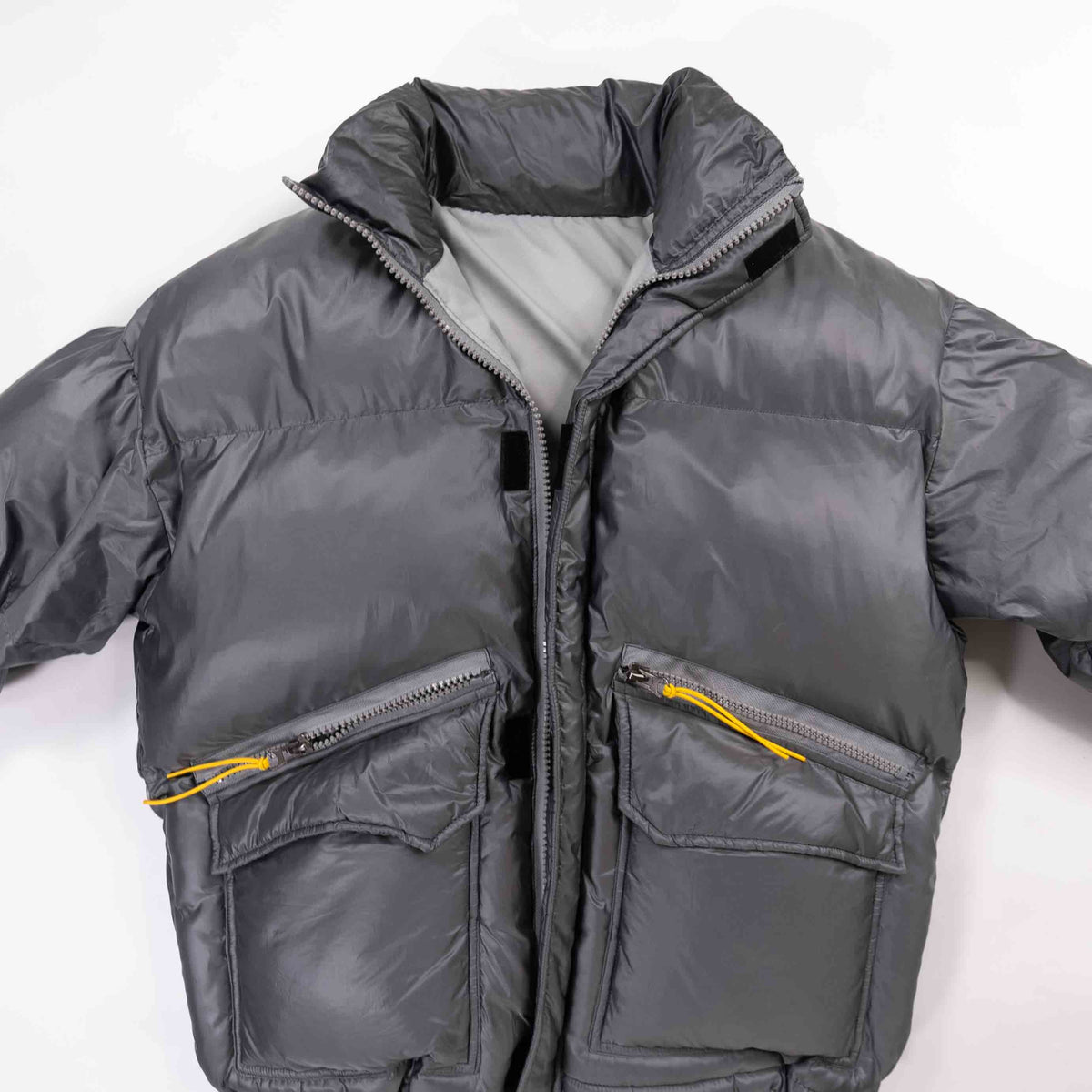 Gray padded round jacket with zippers and pockets.