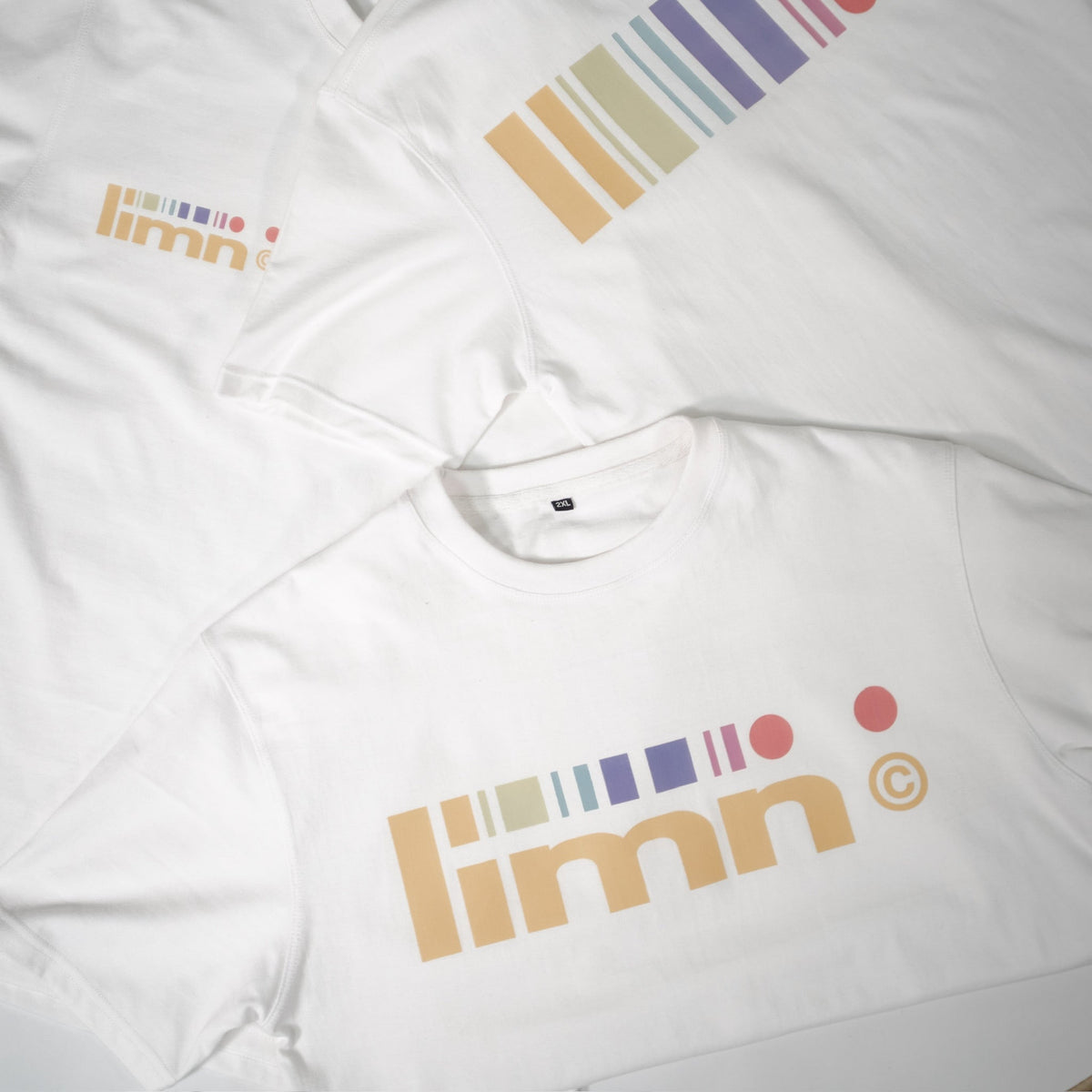 White t-shirts with colorful &quot;limn&quot; logo design, showcasing upcoming fashion release.