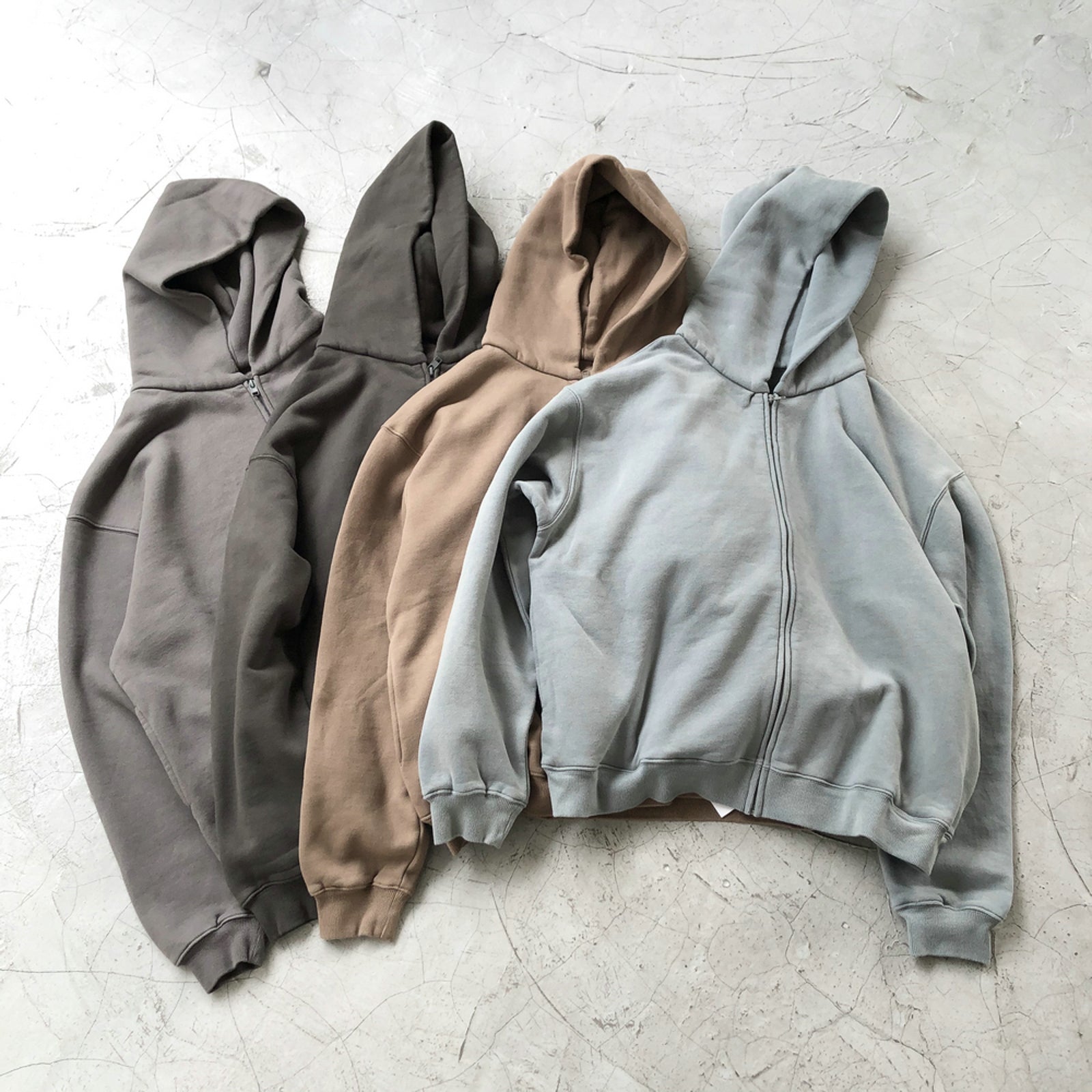 Aqua Zip-up Hoodie in various colors laid out on a textured surface.