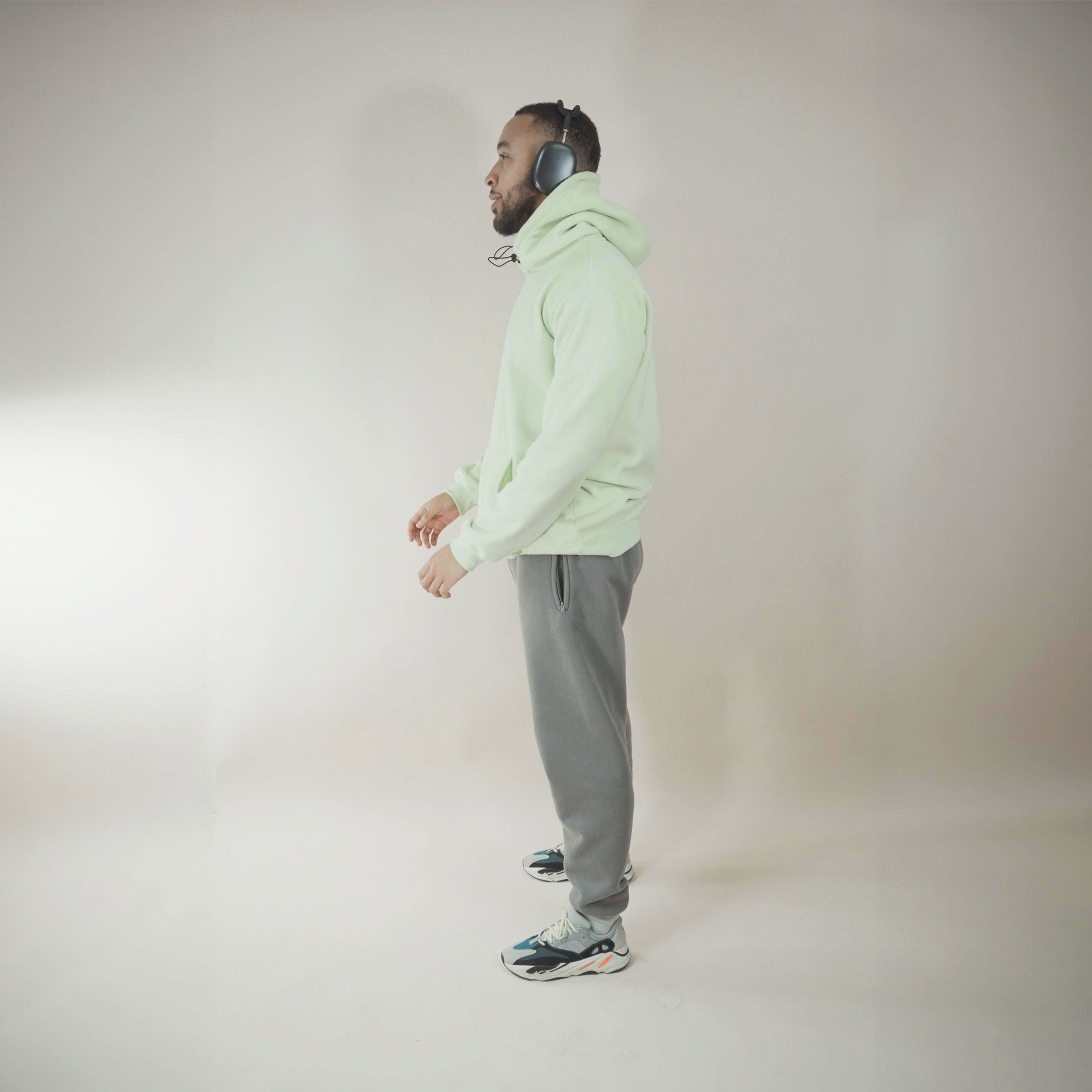 Man wearing cozy fleece lined hoodie and headphones in a neutral room.