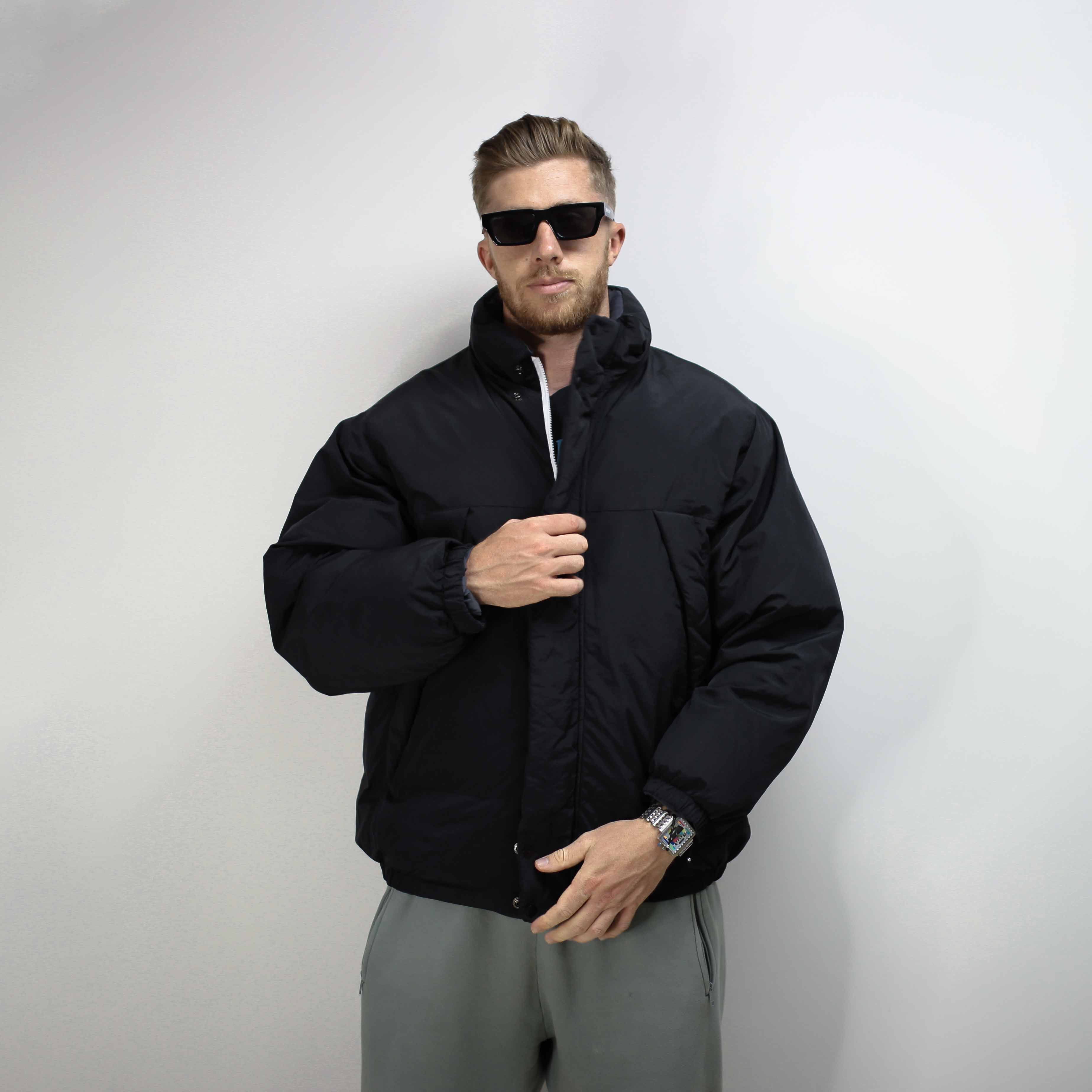 Black flight jacket with a padded design worn by a model with sunglasses.