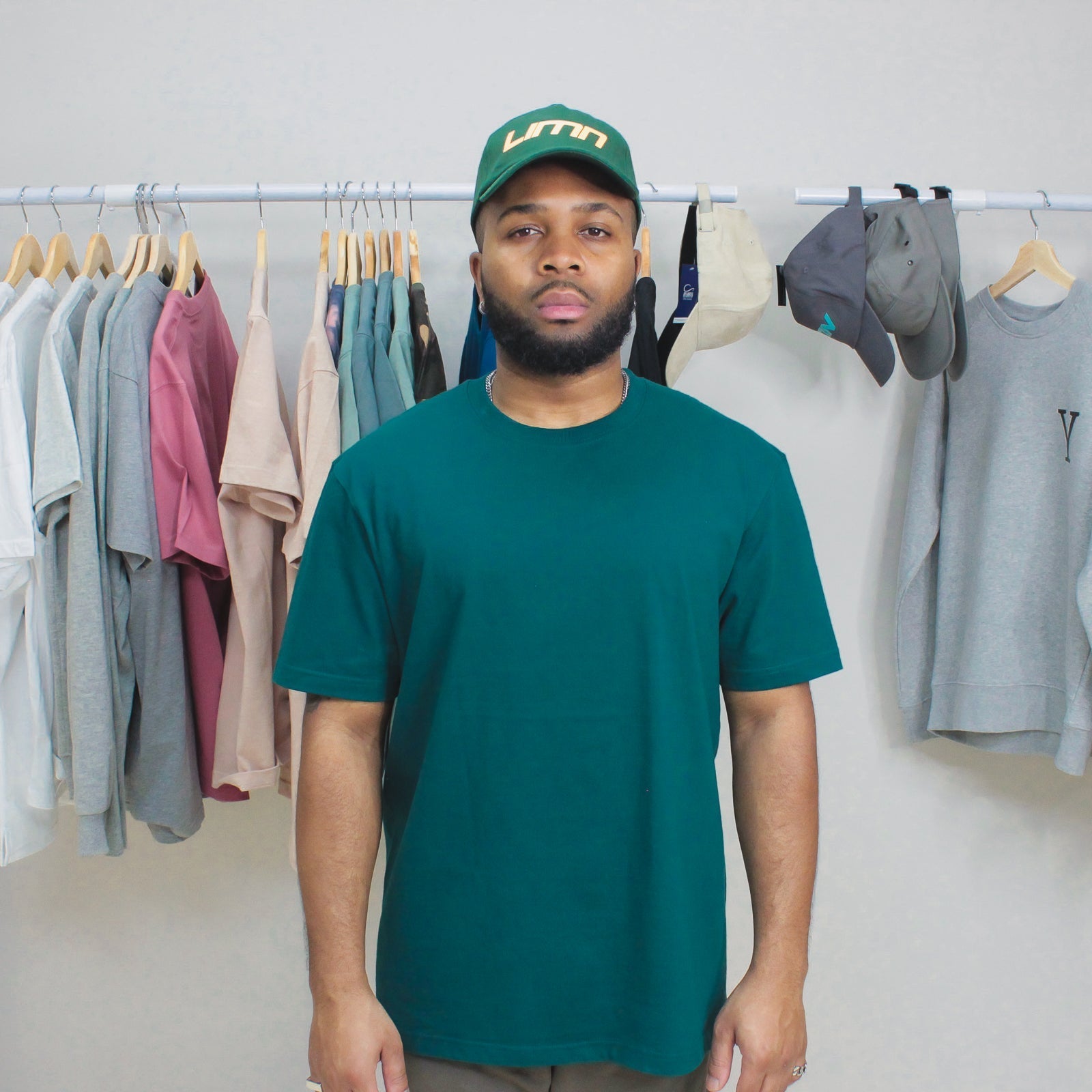 Jade Green Winter Tee on display with clothing rack in background.