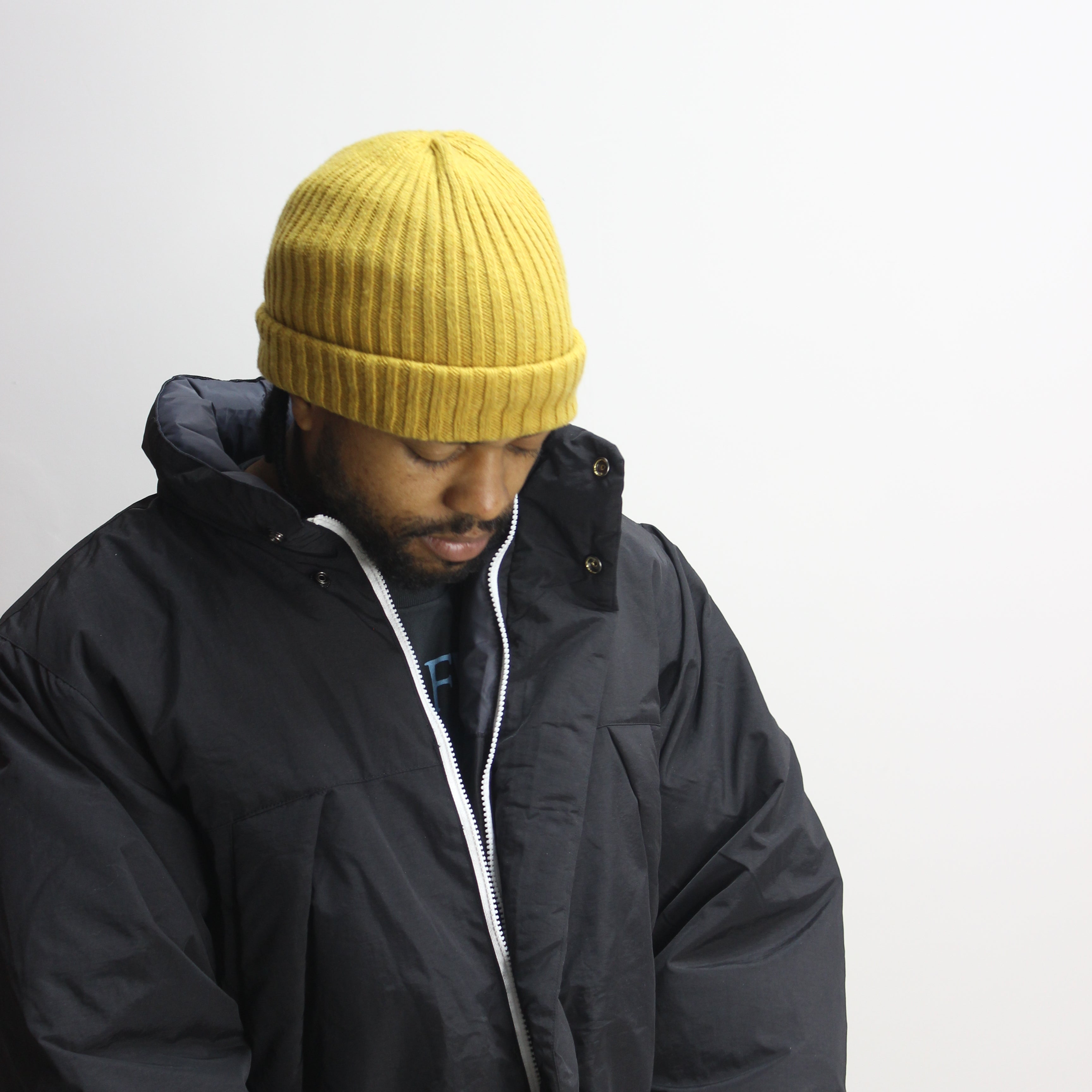 Man wearing black flight jacket and yellow beanie.