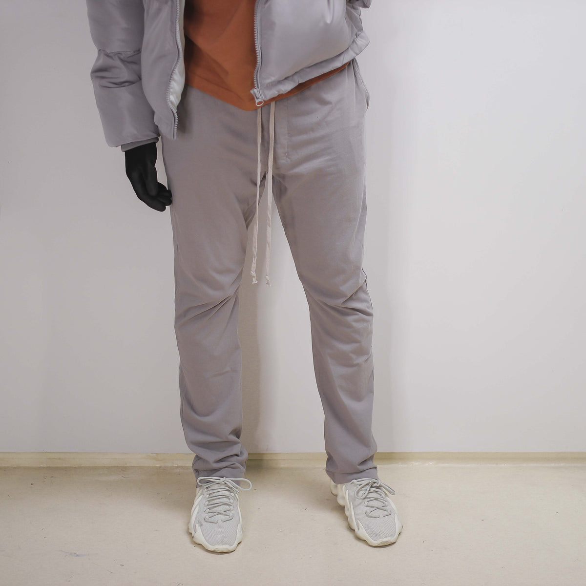 Grey drawstring pant worn by standing model with casual outfit.