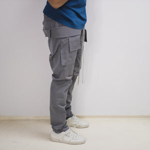 model wearing gray cargo trouser facing away, cream yeezy calabasas power-phase on foot, sapphire blue winter t-shirt