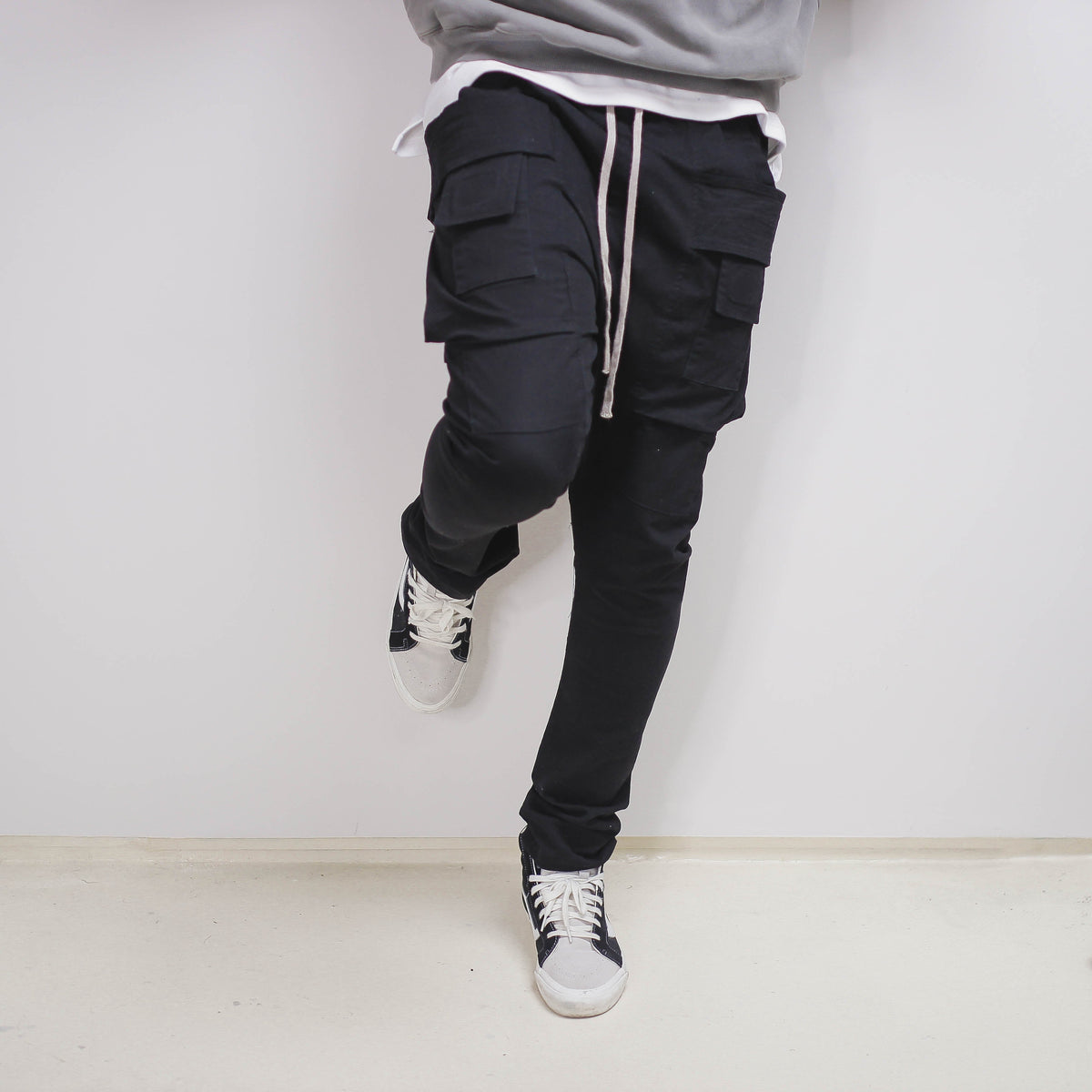 Black slim cargo pant with side pockets, styled with sneakers.