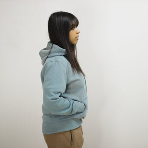female model looking away from camera, azure blue cotton hoodie, tan premium joggers, brown hair
