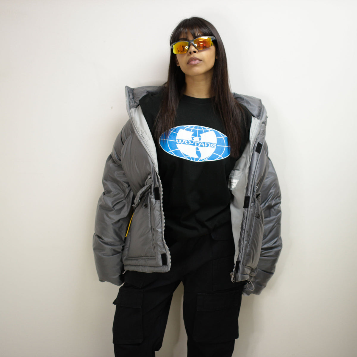 Model wearing a Padded Round Jacket with sunglasses, featuring a globe graphic t-shirt underneath.