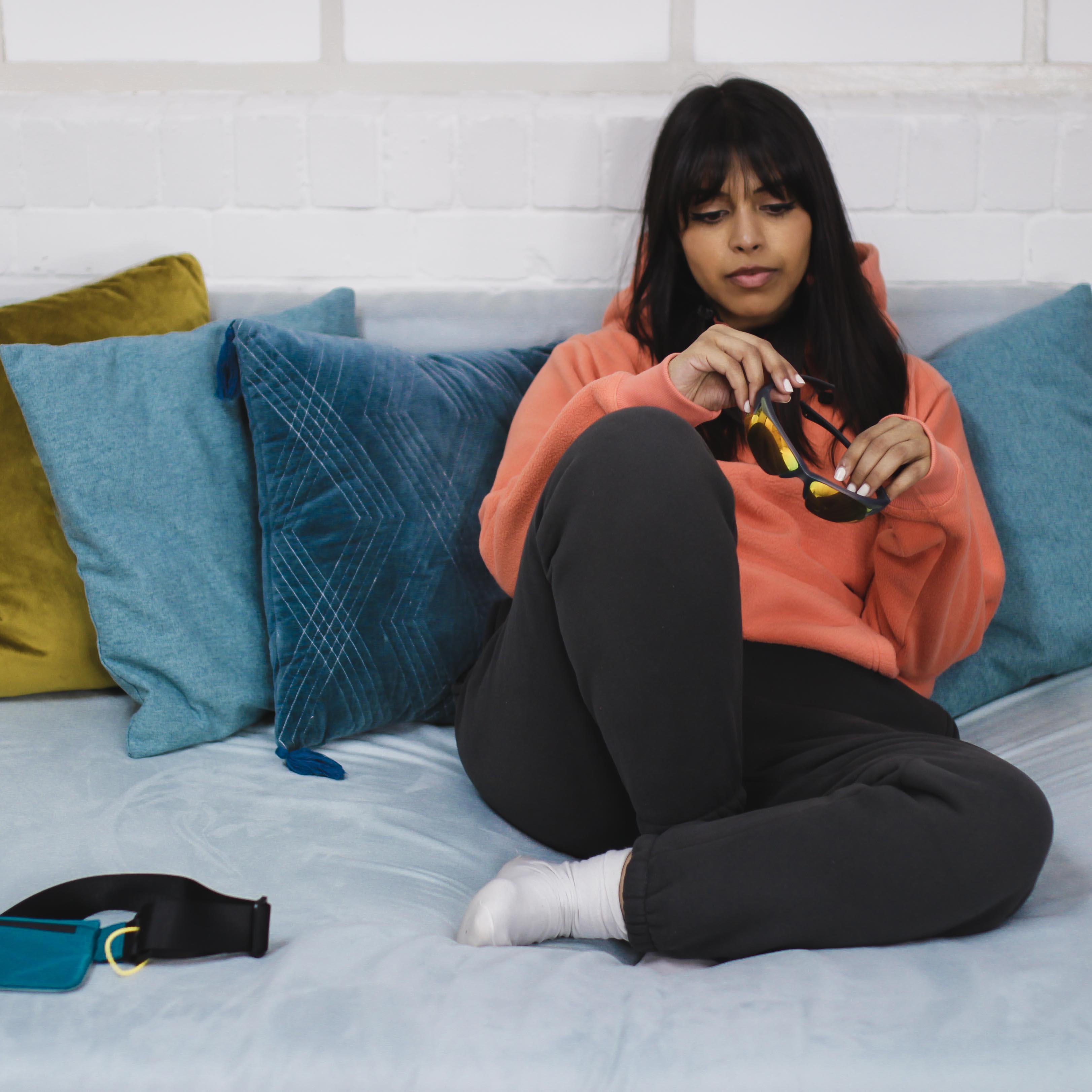 Woman wearing Cozy Peach Hoodie sitting on a couch.