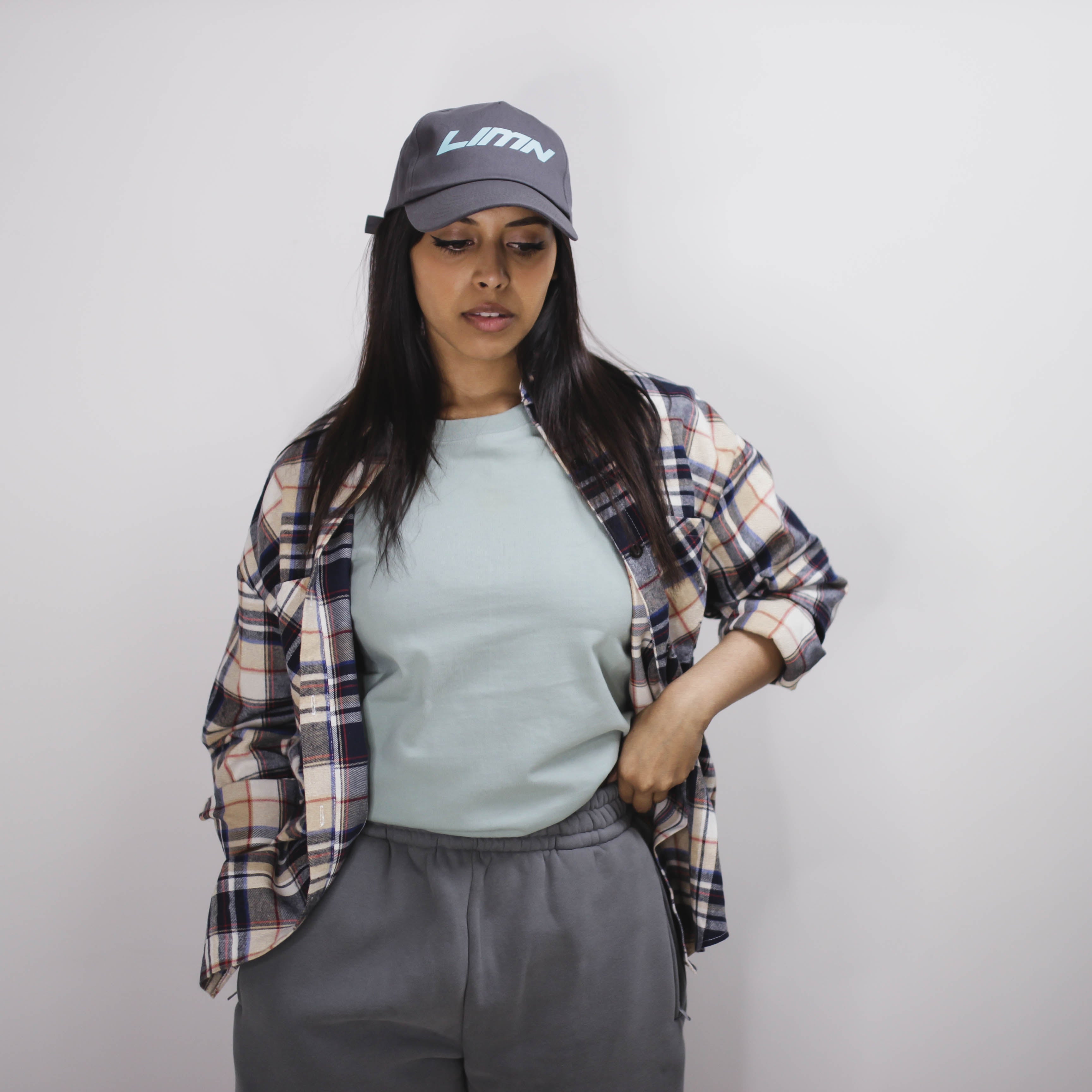 Woman wearing Mint Winter Tee with plaid shirt and gray cap.