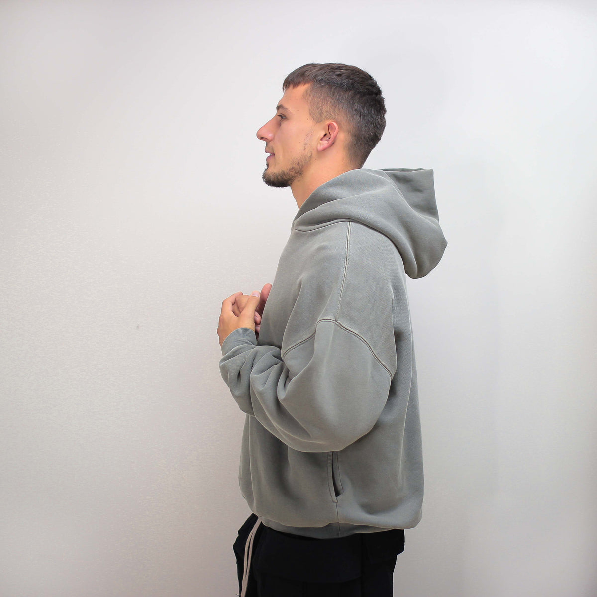 Gray round hoodie worn by a person, side view.