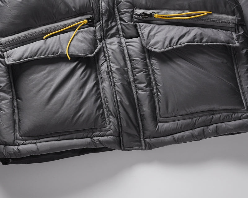 Close-up of gray Padded Round Jacket with pockets and yellow zippers.