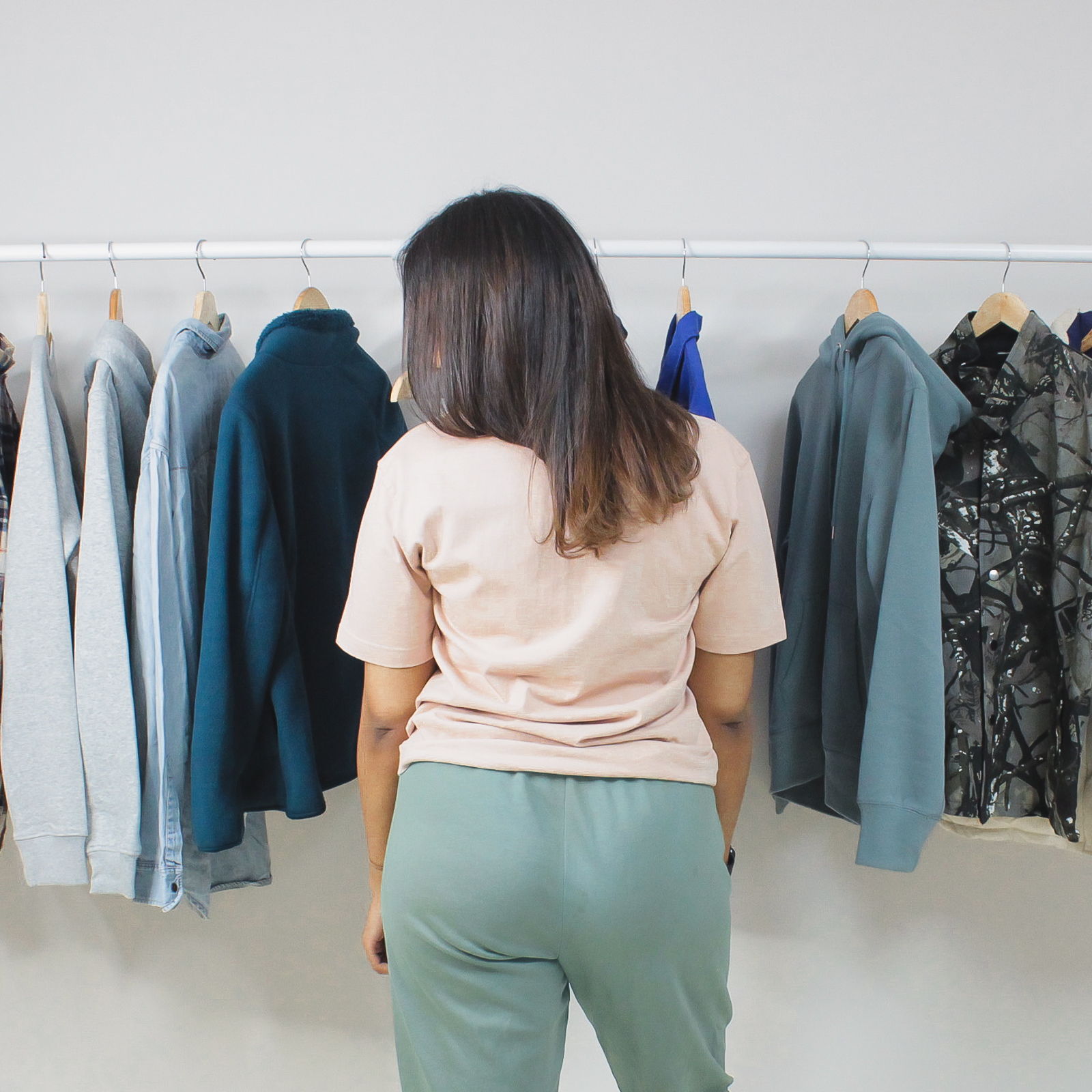 Oversized peach tee on woman in front of clothing rack.